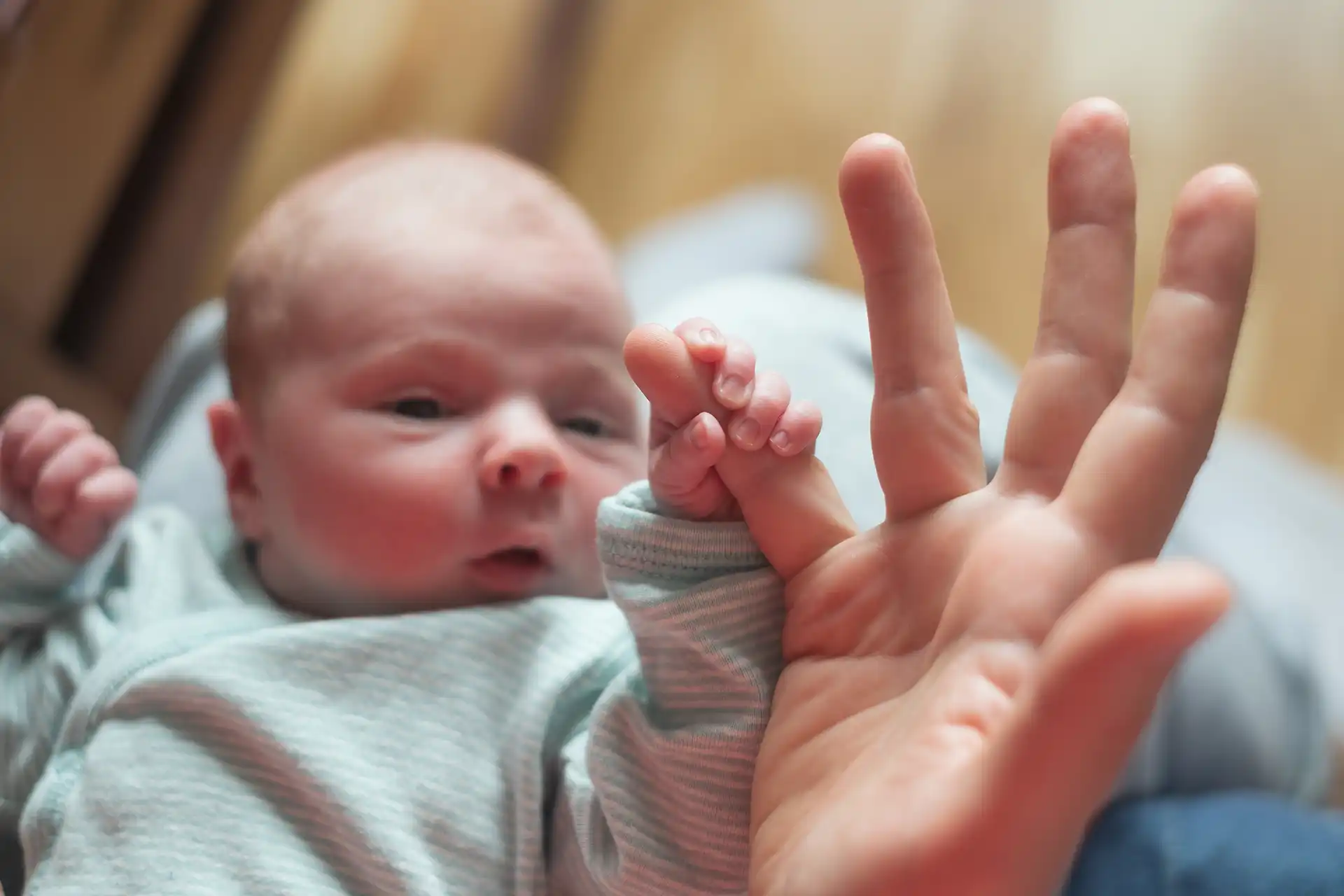 Baby, das den Finger seiner Mutter hält